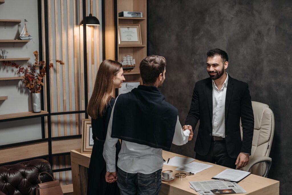 Couple Shaking Hands with Employee at Office
