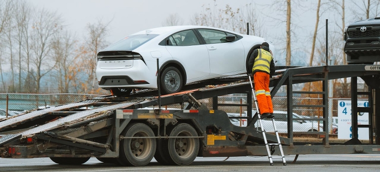 A car is being loaded onto a transportation shipping truck. 