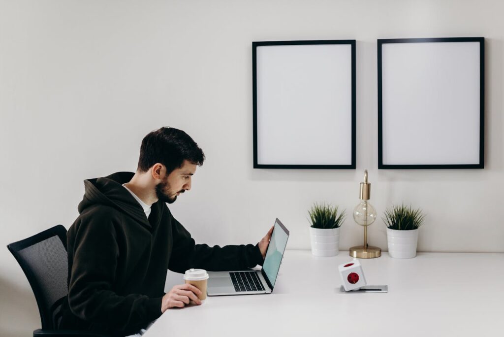 man using his laptop and holding coffee