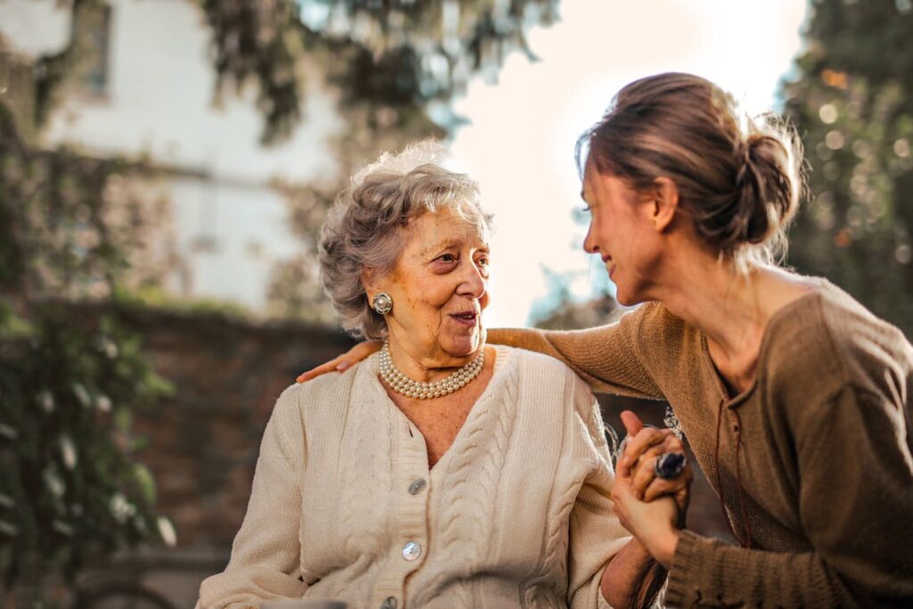 Joyful adult daughter greeting happy surprised senior mother in garden
