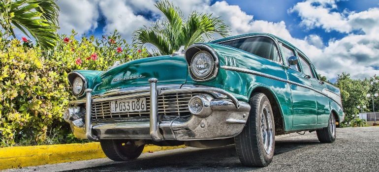 Green convertible in the parking lot surrounded by palm trees and flowers