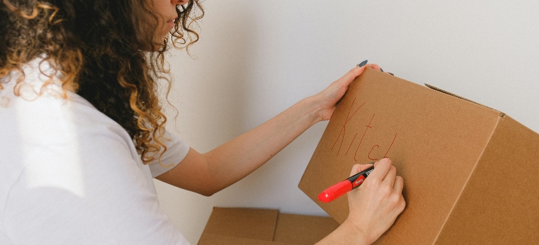 Girl marks box before moving from San Diego to Chicago.