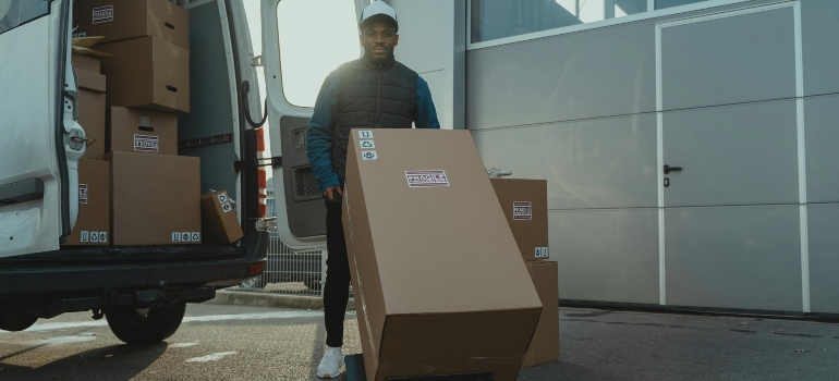 Delivery Man pulling a Trolley with Carton Box for people that are moving from Maine to Arizona