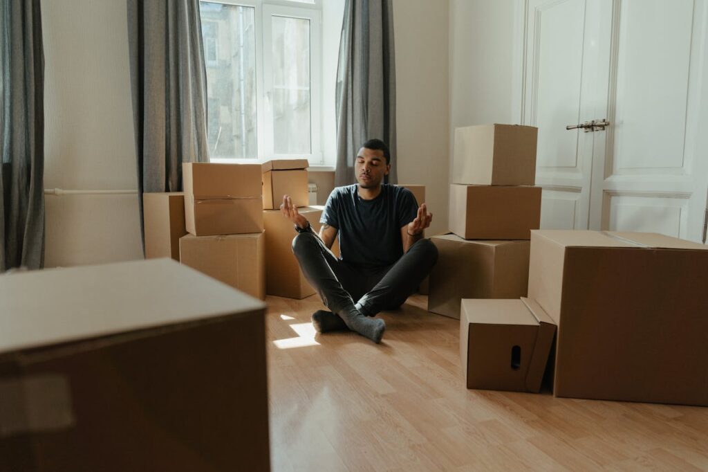 Man in Blue Long Sleeve Shirt Sitting on Black Leather Armchair after trying to pack for a move