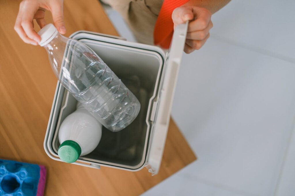 Crop person disposing plastic bottles into container
