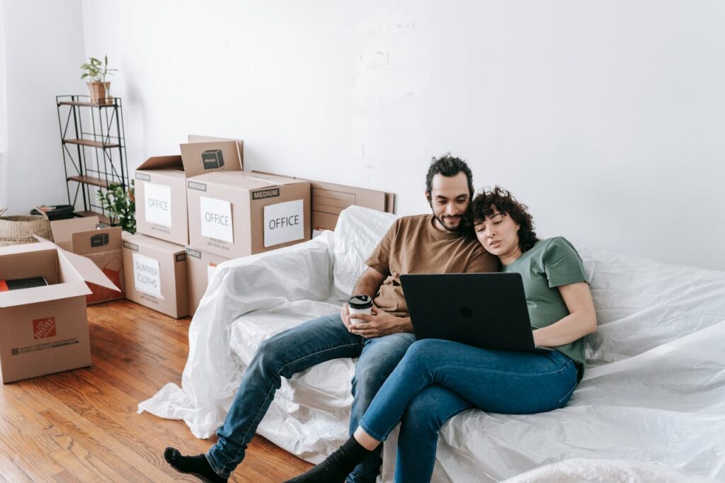 Couple Sitting On A Couch Browsing On computer, reading about Extra Steps You Need to Take for a Safe Long Distance Move