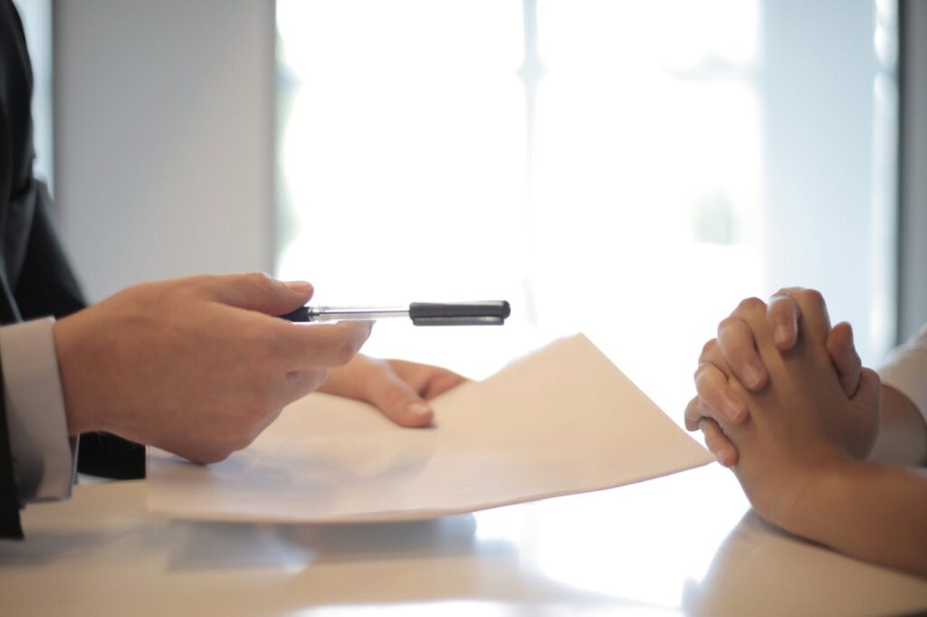Crop businessman giving contract to woman to sign
