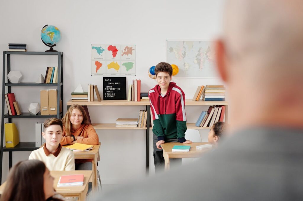 Boy in Red and Green Hoodie Standing in the Classroom
