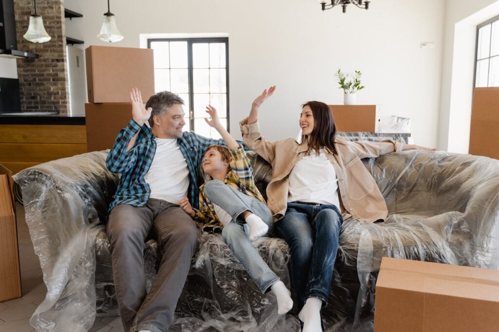 Happy Family Sitting on the Couch Covered with Plastic