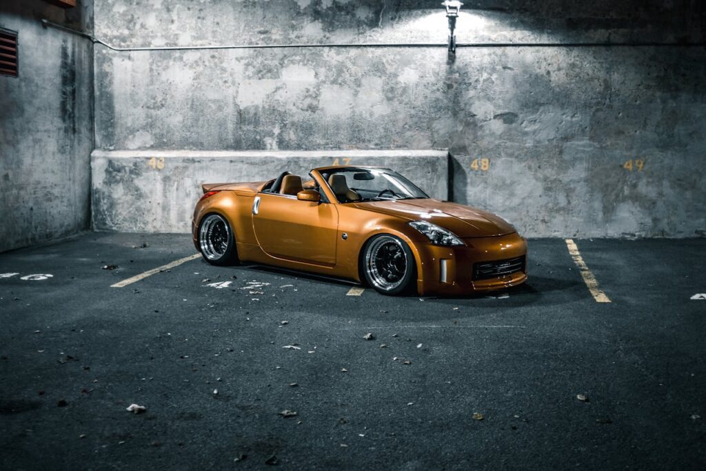 Modern racing car on pavement near shabby wall at night