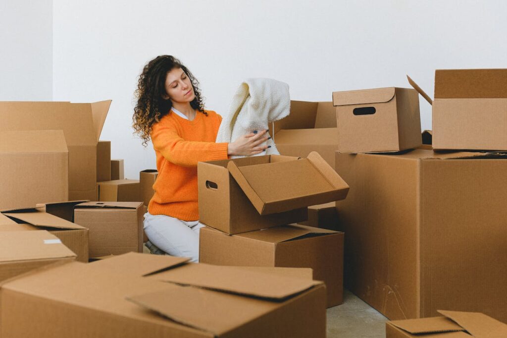 Thoughtful young lady packing clothes into boxes when moving from Maryland to Georgia