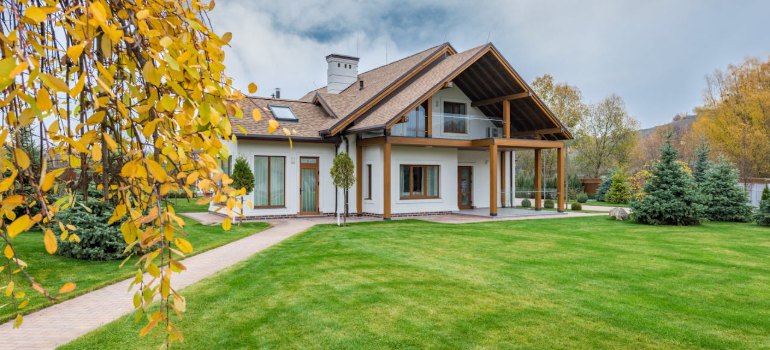 A large family house with a green lawn and autumn trees